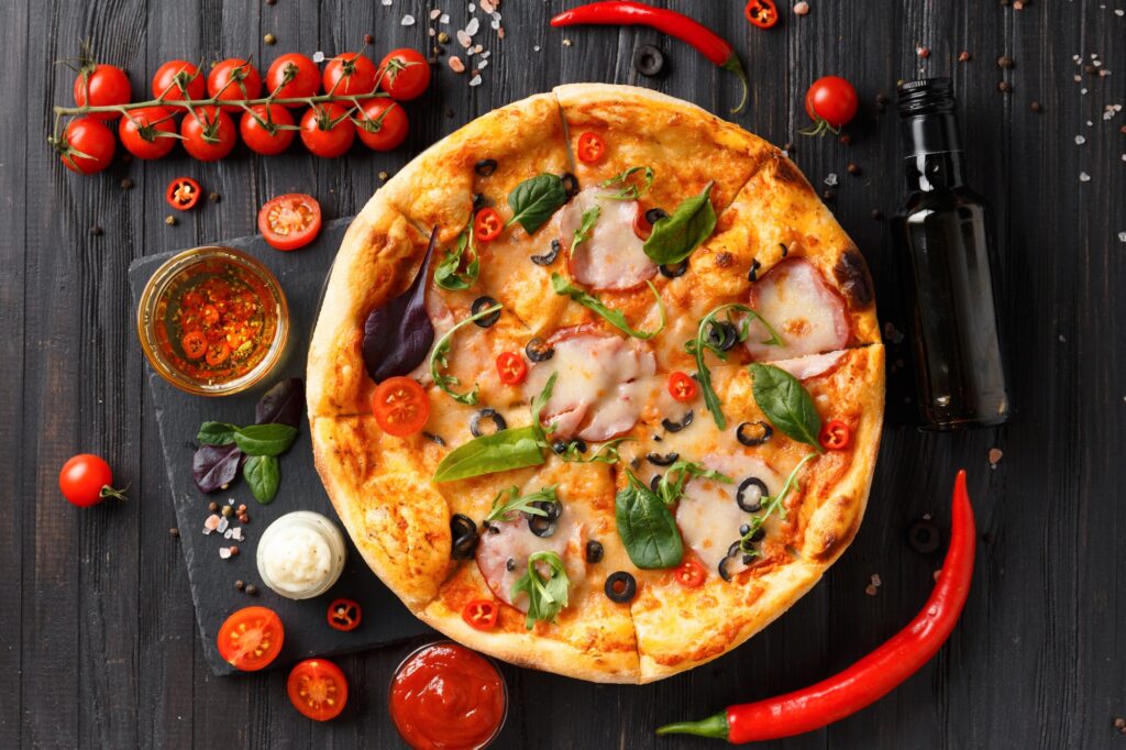 Pizza on a black dish on a dark wooden background top view.